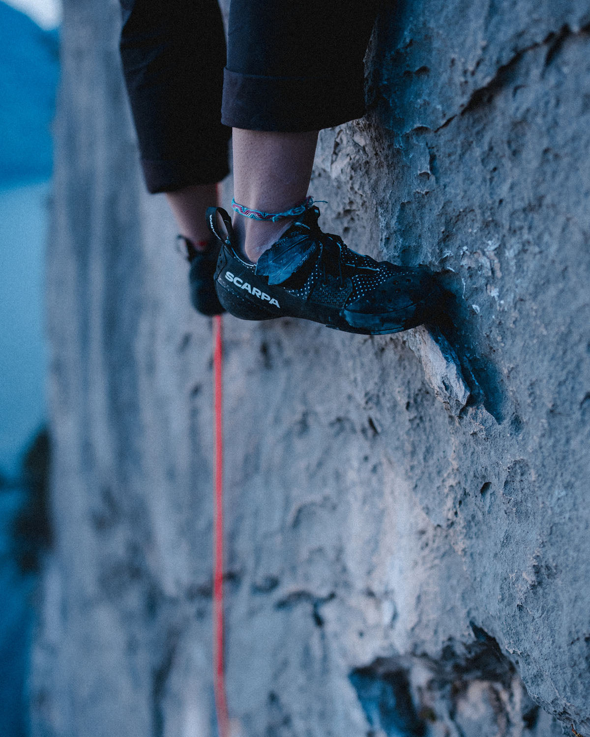 Person climbing a rock wall wearing SCARPA blackbird climbing shoes